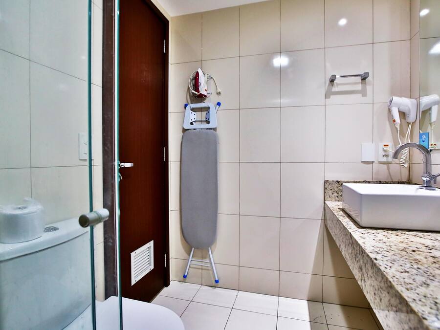 A bathroom with a sink, mirror, and ironing board.