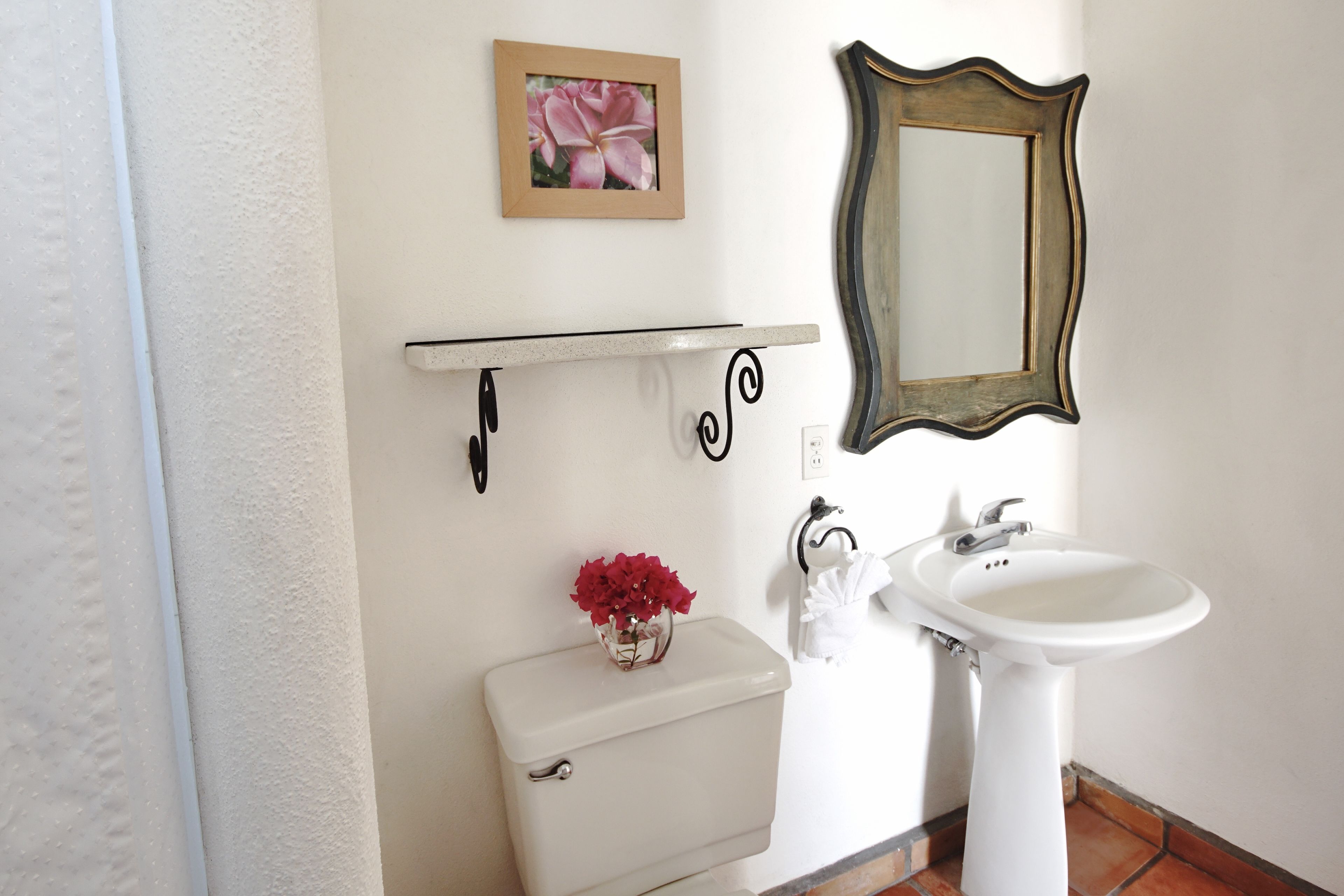 A bathroom with a toilet, sink, and a framed mirror.