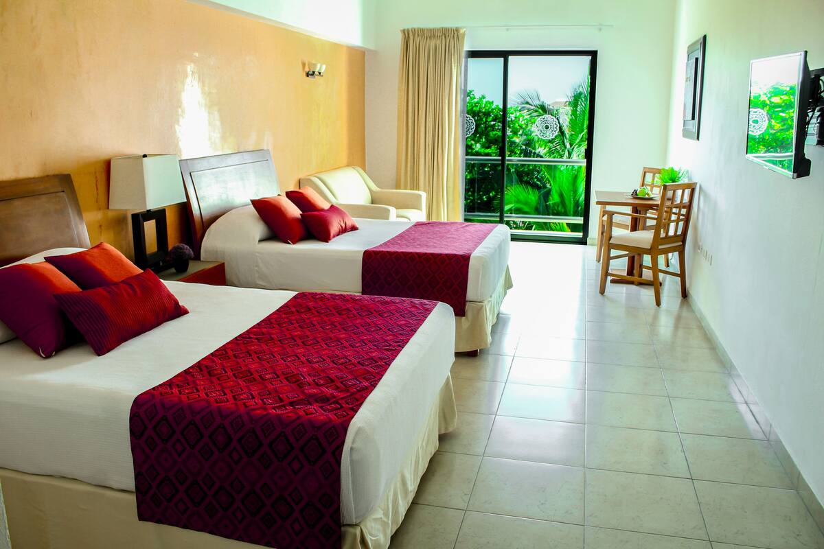 A hotel room with two beds, a small table, and a chair.