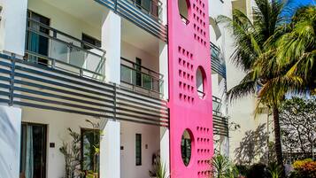 Um hotel moderno com área de piscina, espreguiçadeiras e uma estrutura rosa marcante.