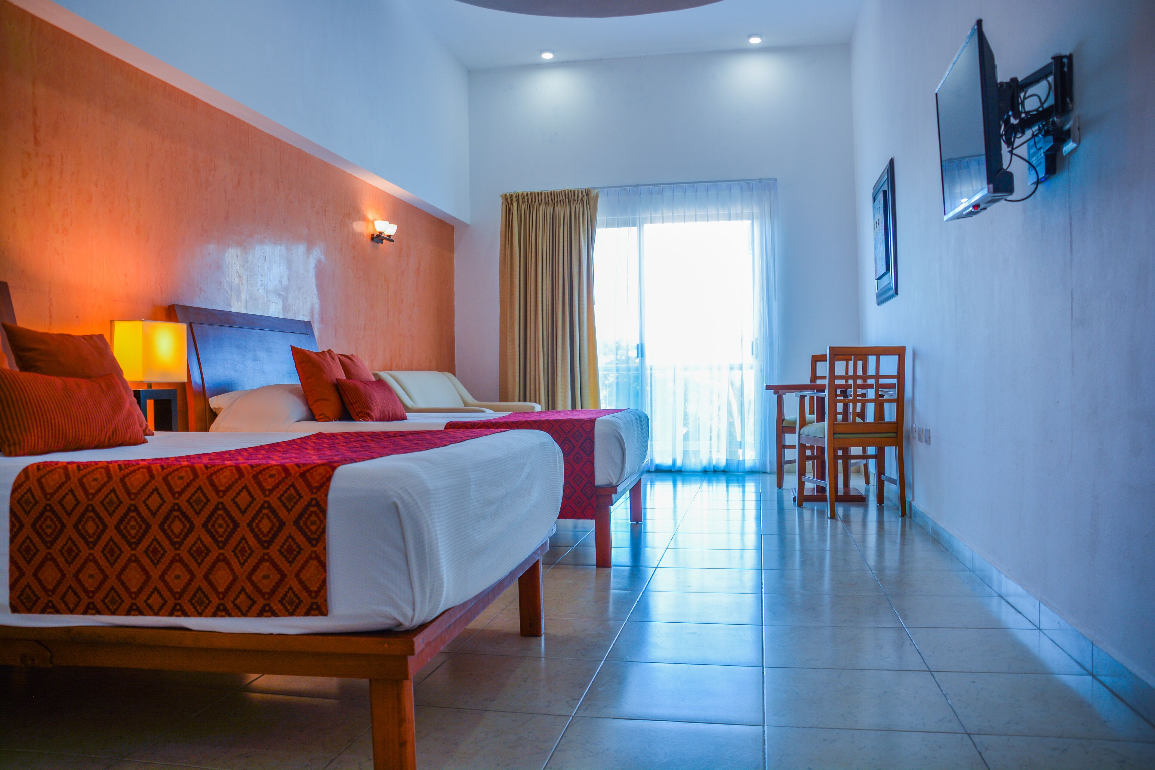A hotel room with two beds, a desk, and a chair.
