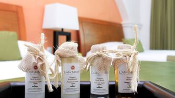 Una bandeja con cuatro botellas de productos orgánicos para el cuidado corporal de Casa Melissa, que incluyen loción corporal, acondicionador, jabón de baño y champú, cada uno con una etiqueta de arpillera.
