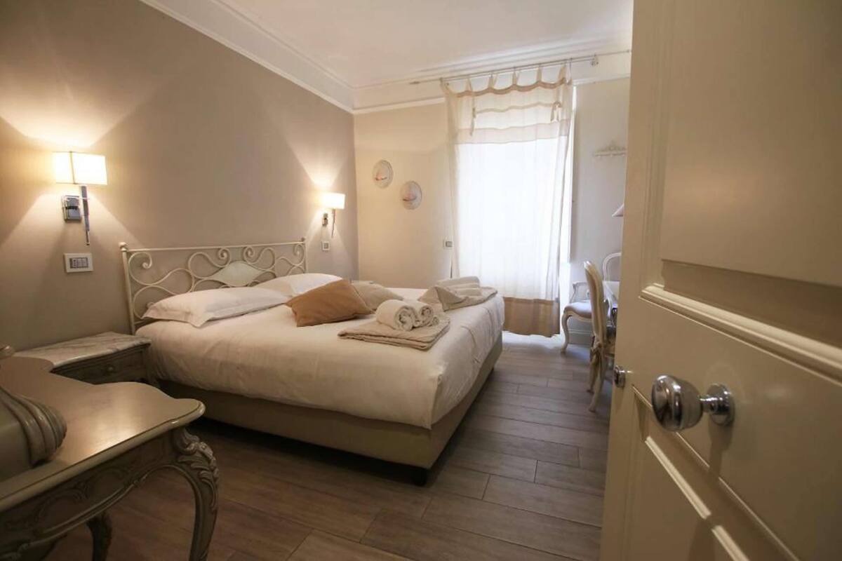 A hotel room with a bed, bedside table, lamp, and a chair.