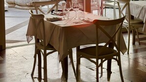 A restaurant with a table set for two, overlooking a body of water during sunset. - Hotel Villa Margherita (Livorno)