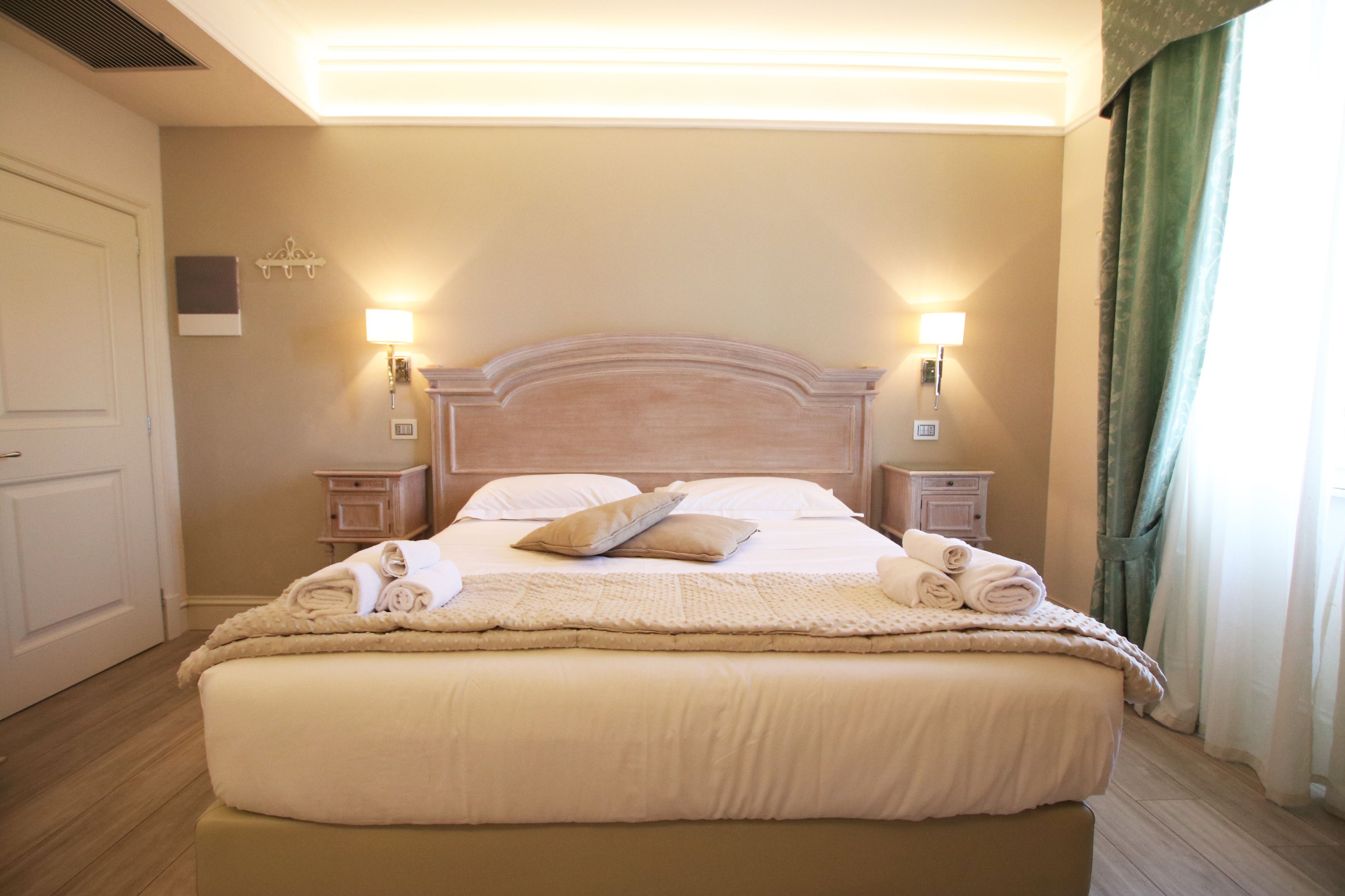 A neatly made bed with a headboard, two bedside lamps, and a bedside table with a lamp.
