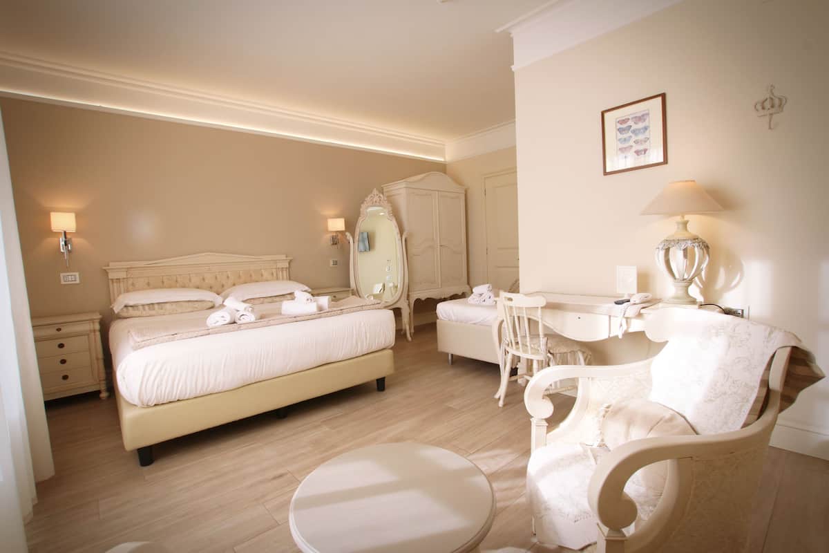 A hotel room with a large bed, a vanity with a mirror, a chair, and a desk.