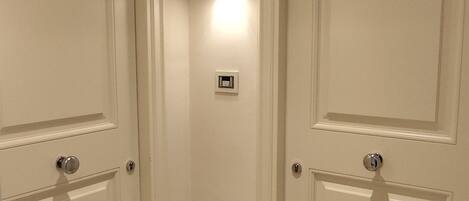 Two adjacent hotel rooms with doors numbered 219 and 218, featuring a light switch and a small electrical outlet on the wall.