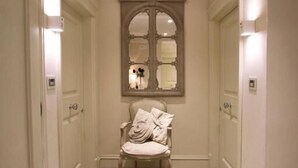 A hallway with a bench, a mirror, and doors on either side. - Hotel Villa Margherita (Livorno)