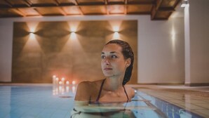 A person in a swimming pool with a tiled floor and a ceiling with wooden beams. - Kunzmann's Hotel (Bad Bocklet)