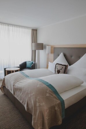 Ett hotellrum med en stor säng, en stol, en lampa och utsikt över omgivningarna.