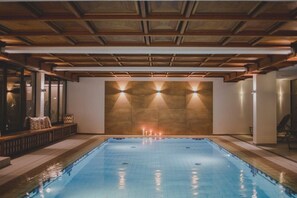 En swimmingpool med ett tak av trä och vägglampor.