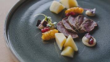 Un plato con carne en rodajas, fruta y pequeñas guarniciones.