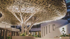 A modern building with a unique perforated ceiling design, indoor plants, and a curved seating area. - Kunzmann's Hotel (Bad Bocklet)