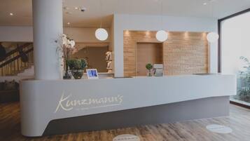 Un comptoir d’accueil au design moderne, avec un mur revêtu de panneaux en bois et un comptoir blanc.