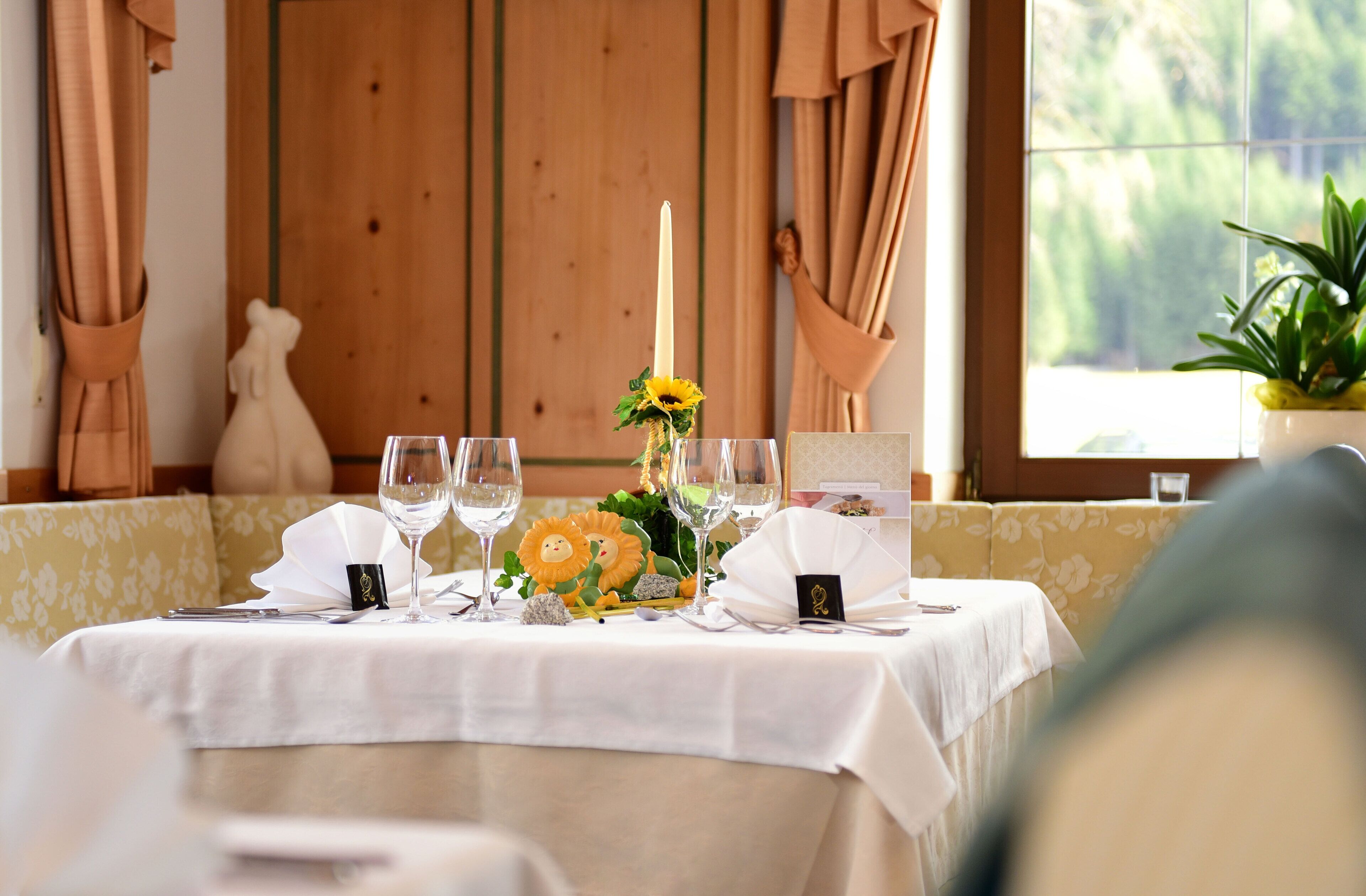 A table set for dining with a candle centerpiece, a menu, and a potted plant.