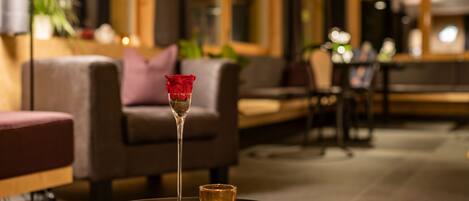 A cozy seating area with a round table, a candle, and a glass with a rose.