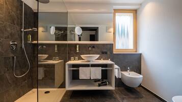 Un bagno moderno con doccia vetro, lavandino bianco e bidet.