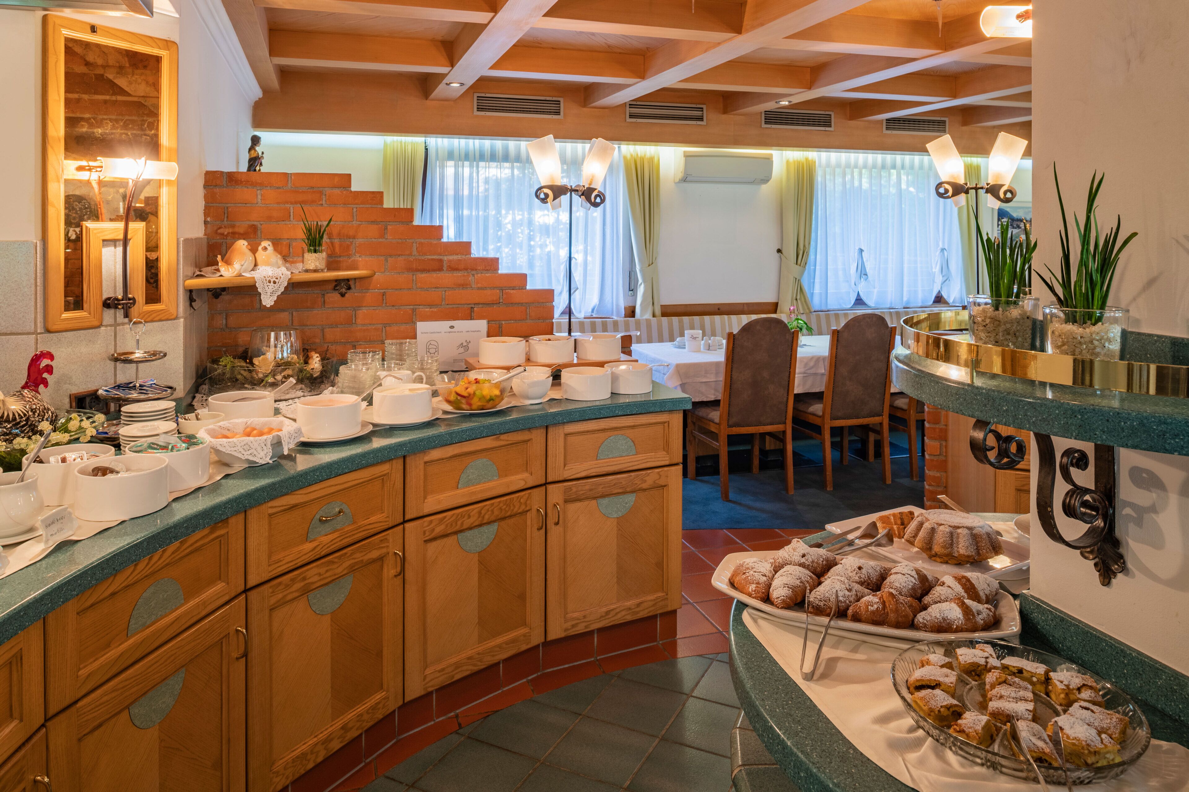 A breakfast buffet with various food items and a seating area with chairs and a table.