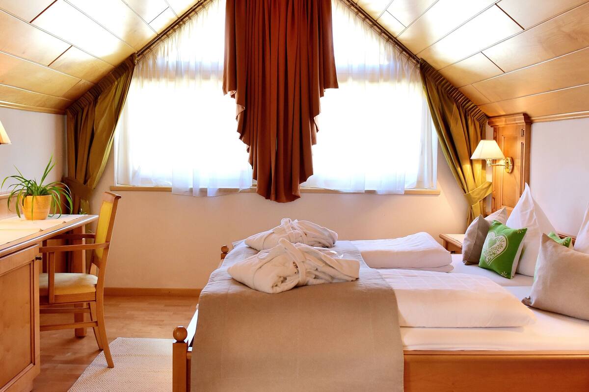 A hotel room with a bed, a desk, a chair, and a window with curtains.