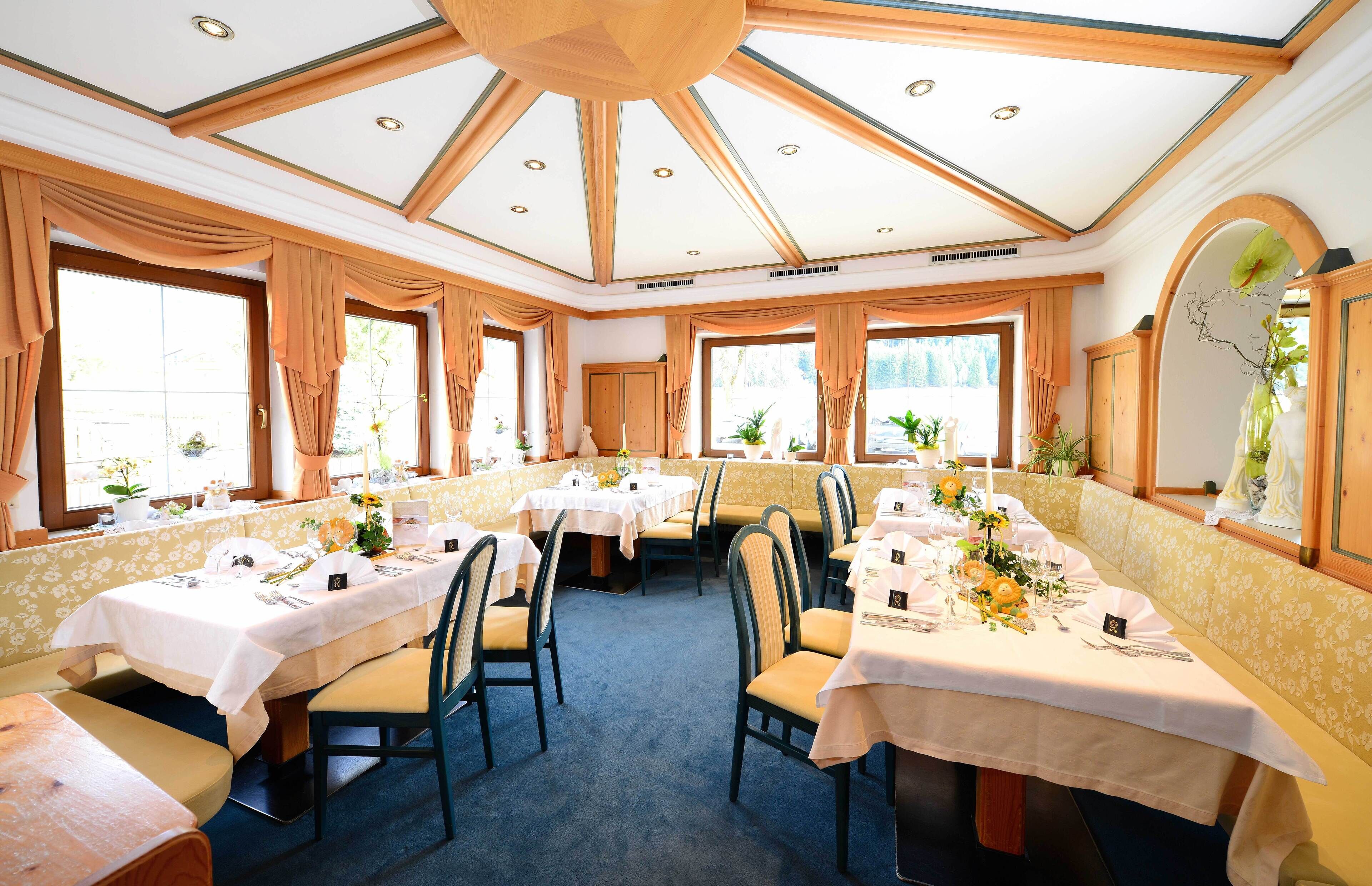 A restaurant with multiple tables set for dining, featuring a high ceiling with skylights and large windows.