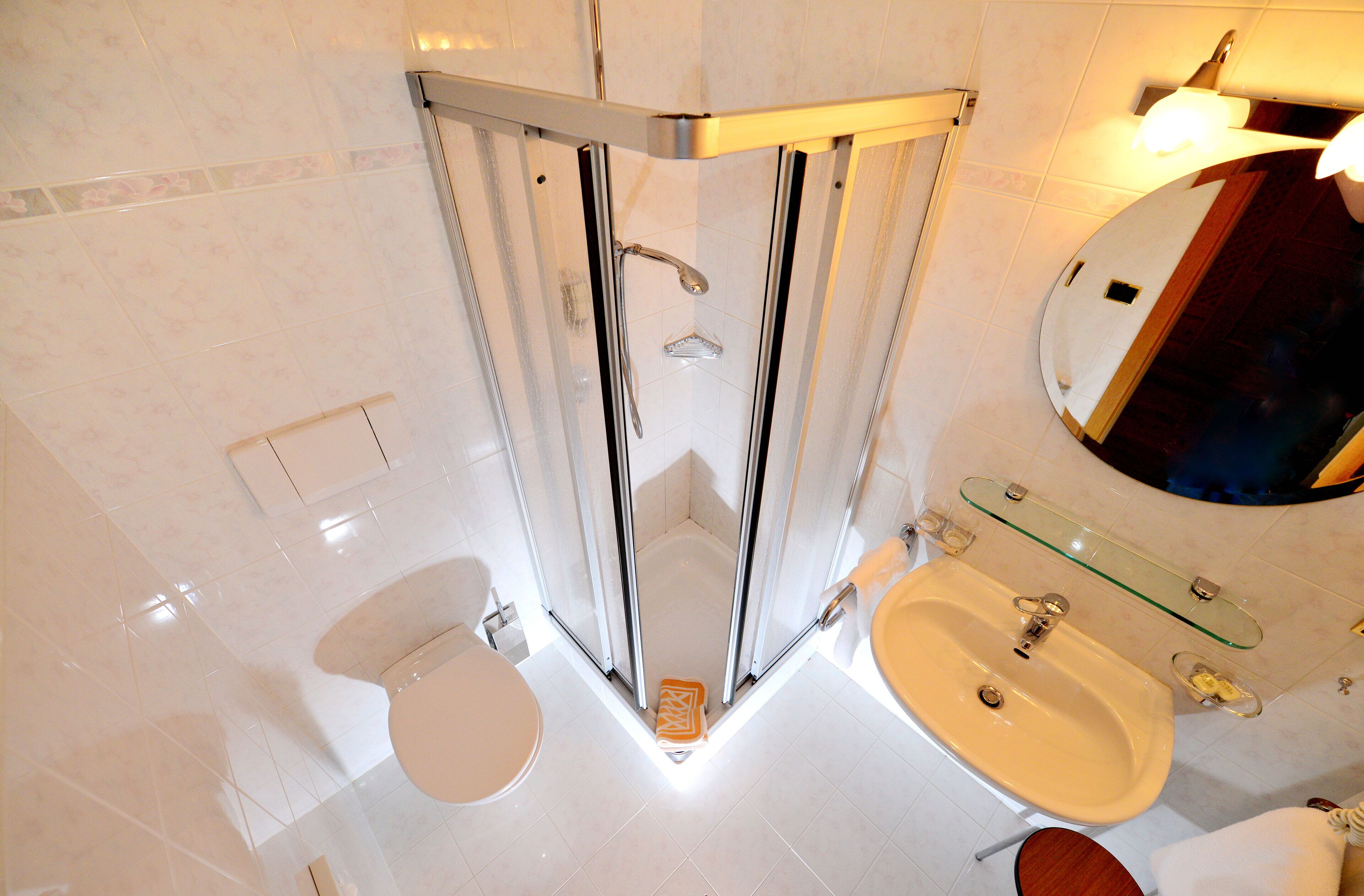 Un baño moderno con ducha de vidrio, un lavabo blanco y un espejo sobre él.