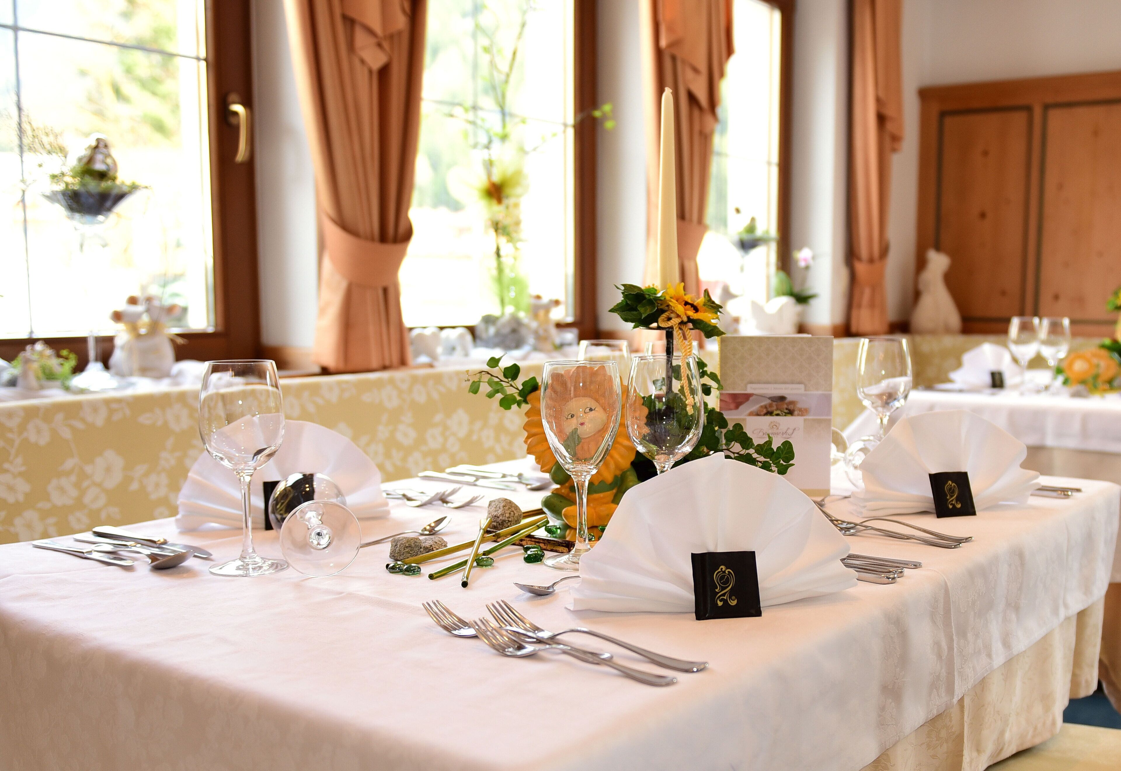A table set for a formal dining event with multiple wine glasses, cutlery, and decorative elements.