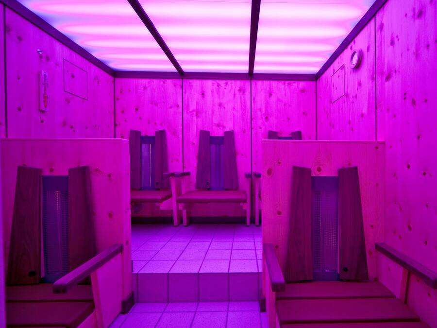 Una habitación con paredes de madera y suelo de baldosas, que incluye dos bancos de madera y una pequeña mesa.