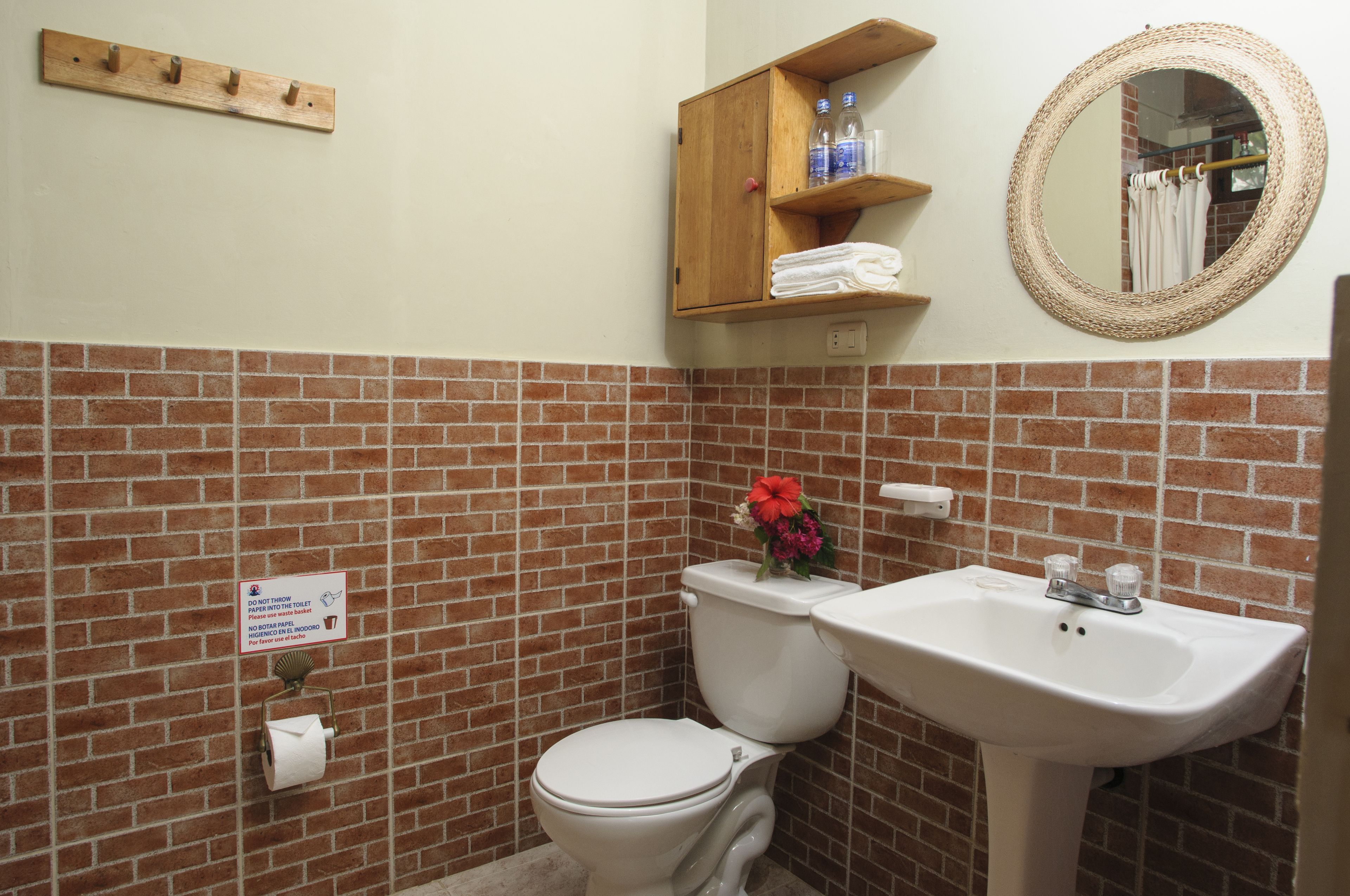 A bathroom with a toilet, sink, and a wooden shelf above the sink.