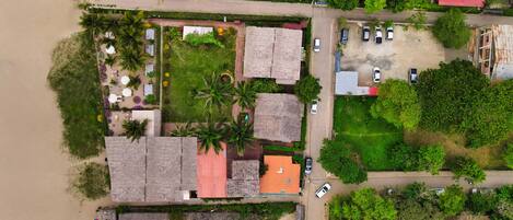 An aerial view of a coastal area with buildings, a beach, and greenery.