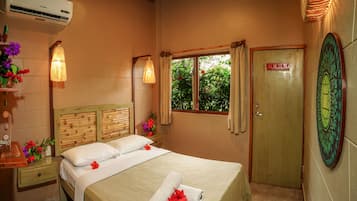 Habitación de hotel con cabecera de madera, cama con ropa blanca, ventana con cortinas y puerta con un letrero.