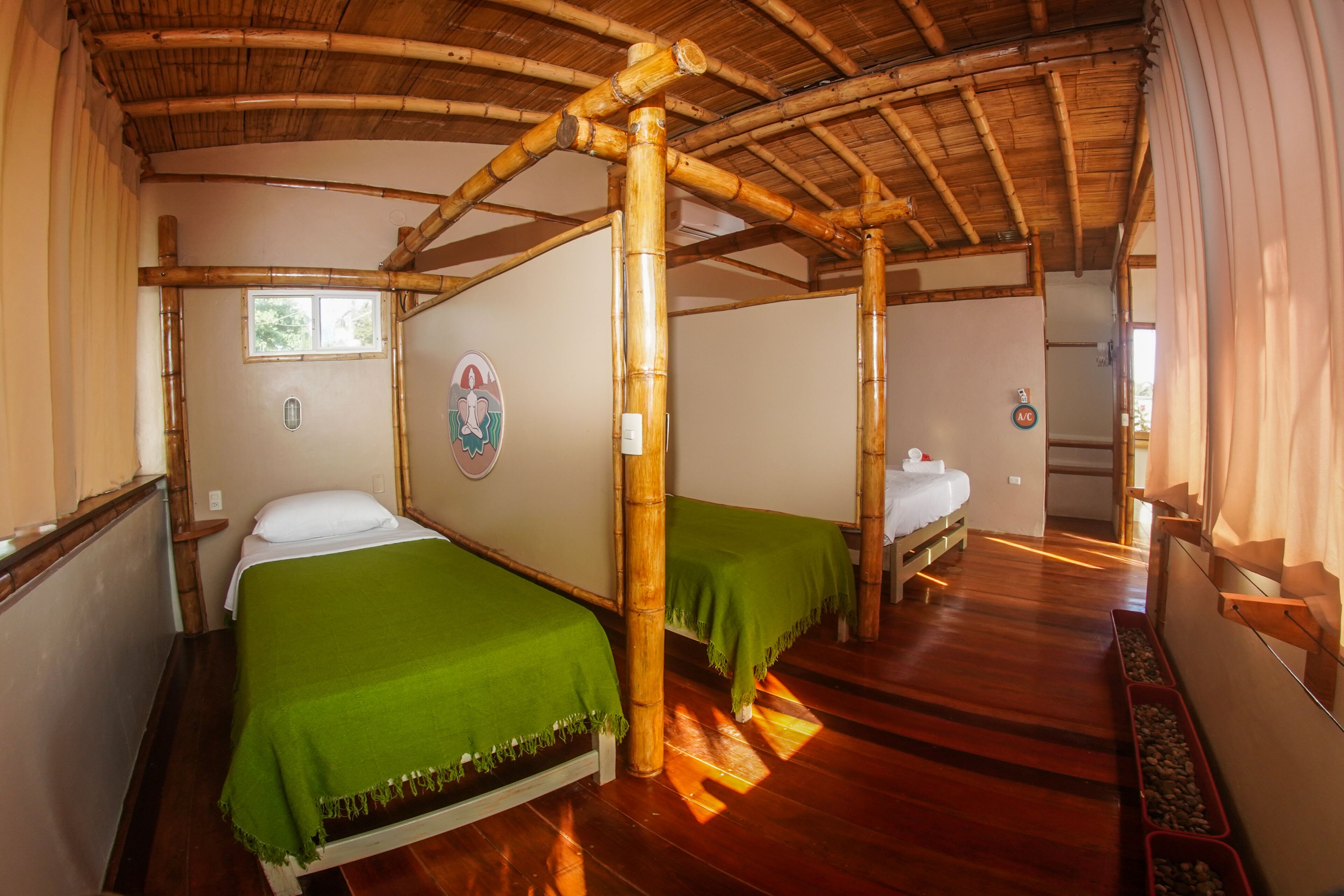 A room with two beds, a bamboo ceiling, and a small window.