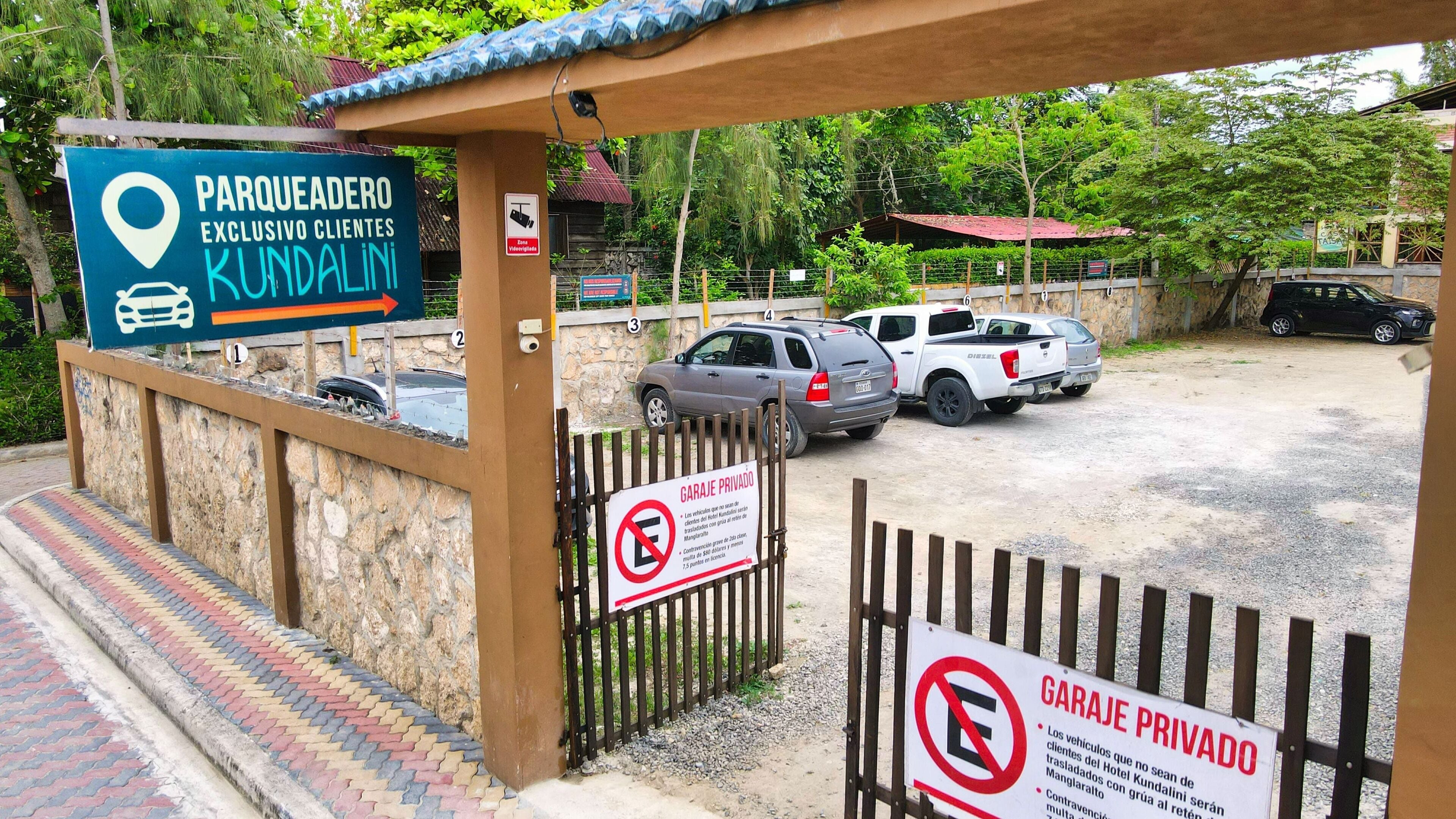A gated parking area with signs indicating private parking and a direction sign for 'Parqueadero Exclusivo Clientes Kundalini'.