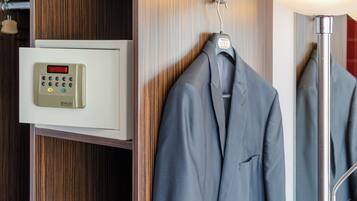 A room with a digital safe, a hanging coat, and a lamp.