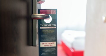 Uma porta com uma placa que diz 'THINK GREEN' e 'BITTE ZIMMER REINIGEN' (por favor, limpe o quarto).