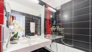 Ein modernes Badezimmer mit einem weißen Waschbecken, einem großen Spiegel und einer Duschkabine.