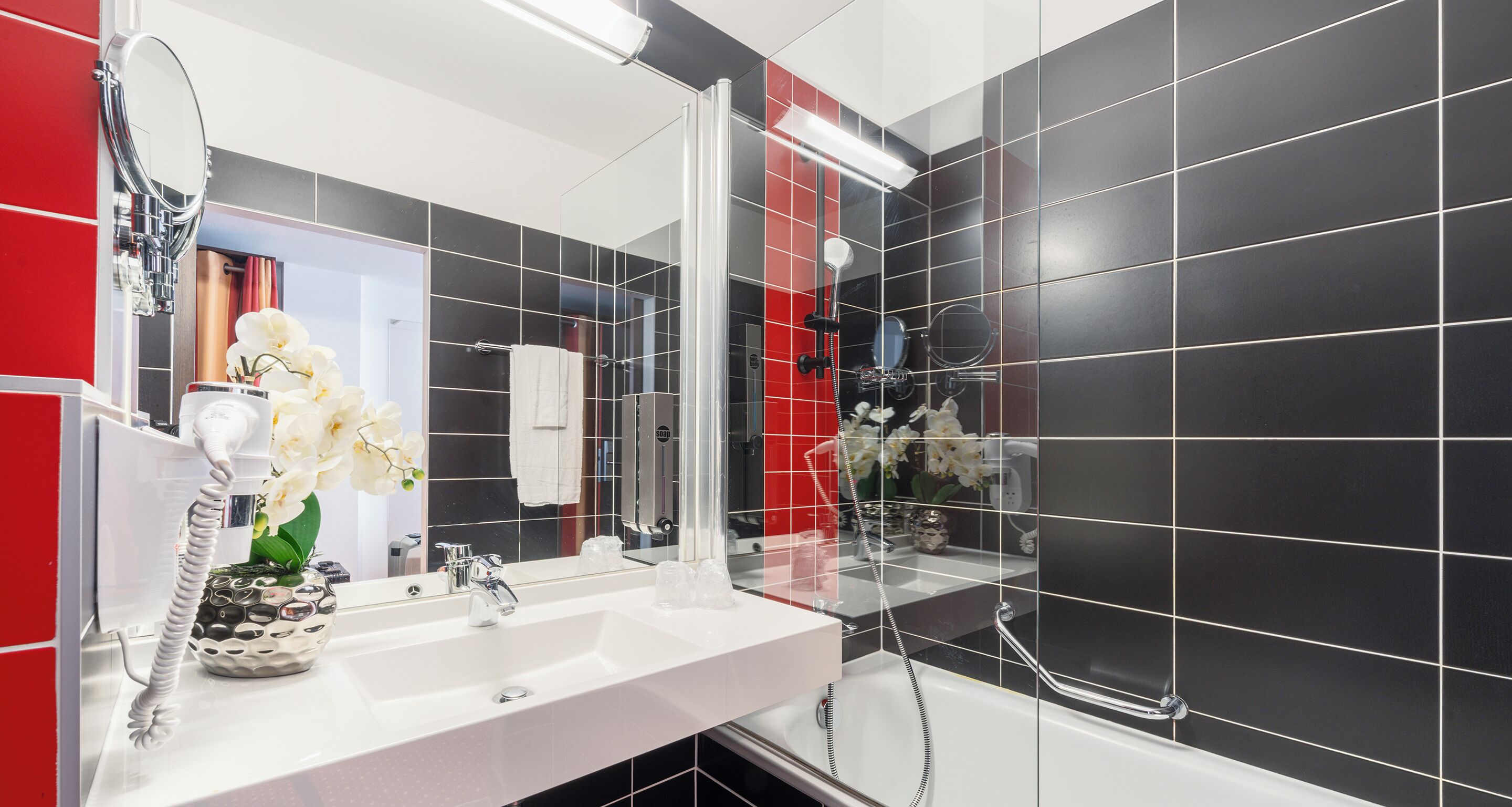 A modern bathroom with a white sink, a large mirror, and a shower area.