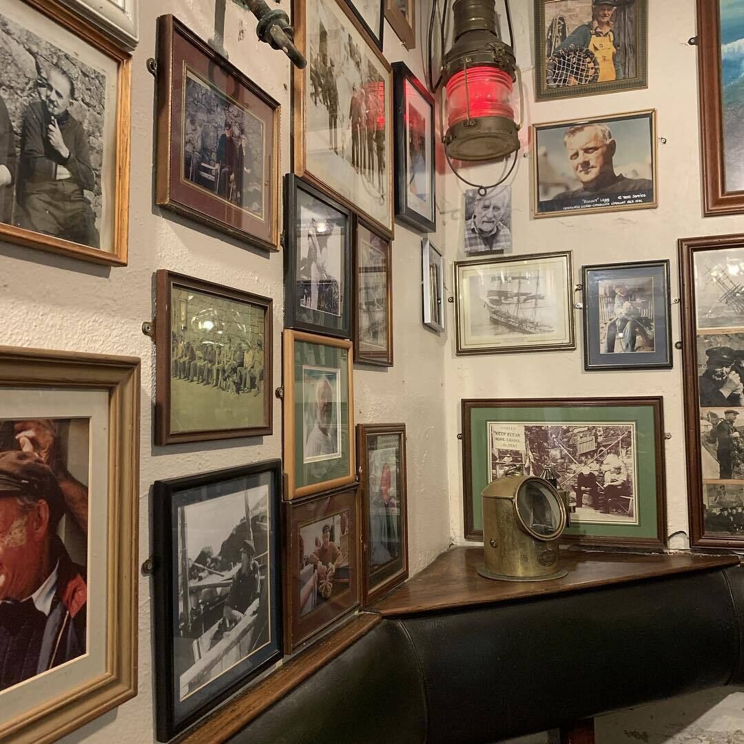 Un mur orné de plusieurs photographies encadrées et d’une lanterne ancienne.