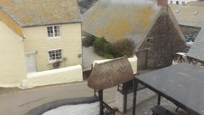 A coastal building with a thatched roof, stone walls, and a view of the sea.
