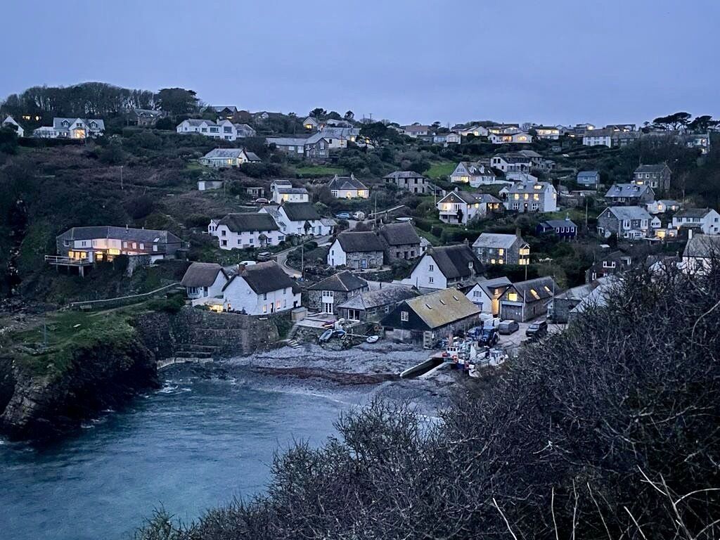 A coastal village with houses along the shoreline, a small pier, and a river.