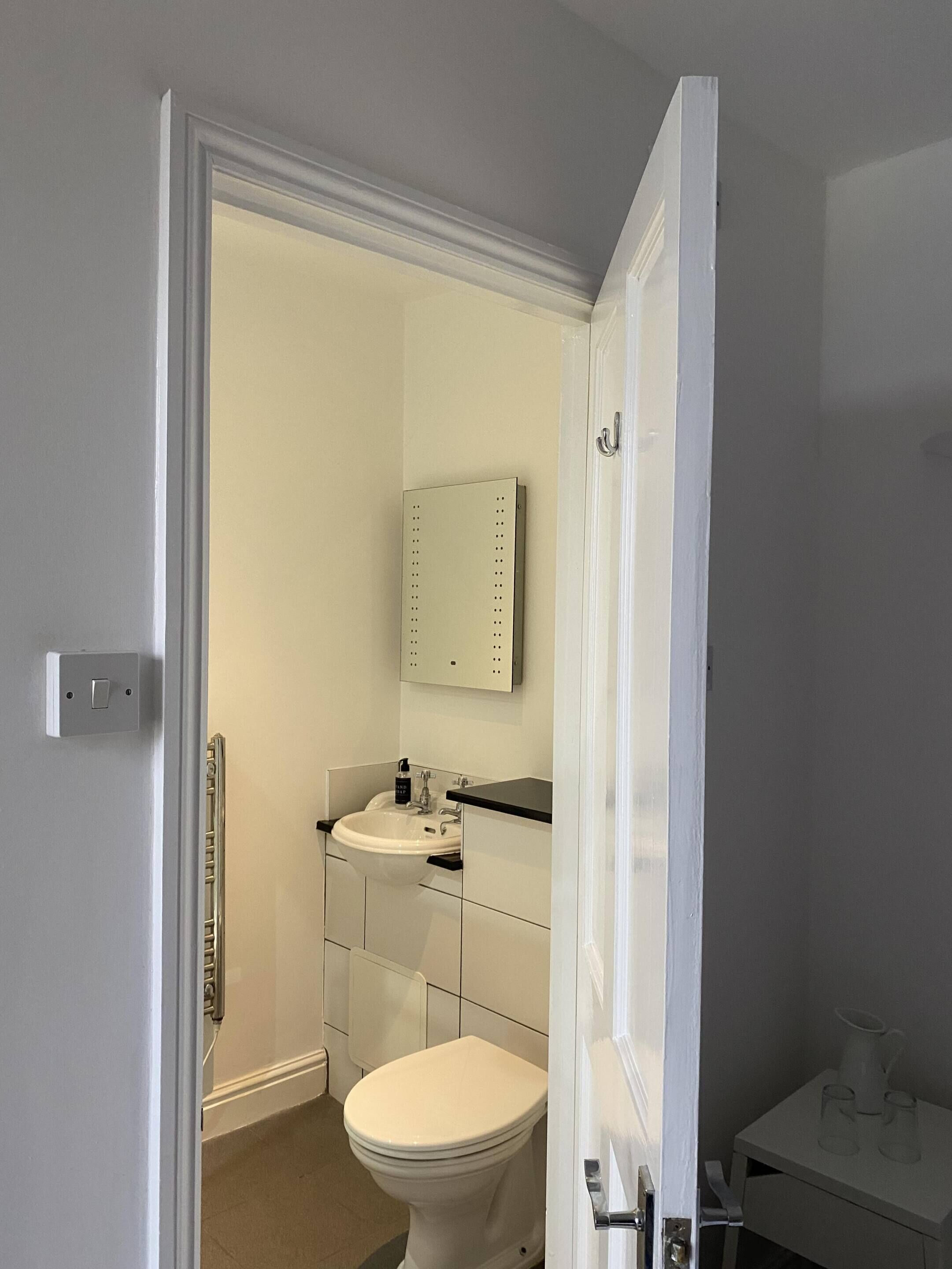 A bathroom with a toilet, sink, and mirror.