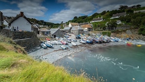 A coastal village with stone buildings and a row of boats docked along the shore.