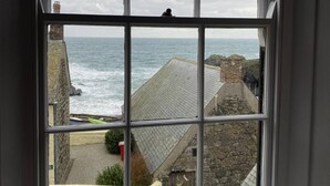 A window with a view of the sea and coastal buildings.