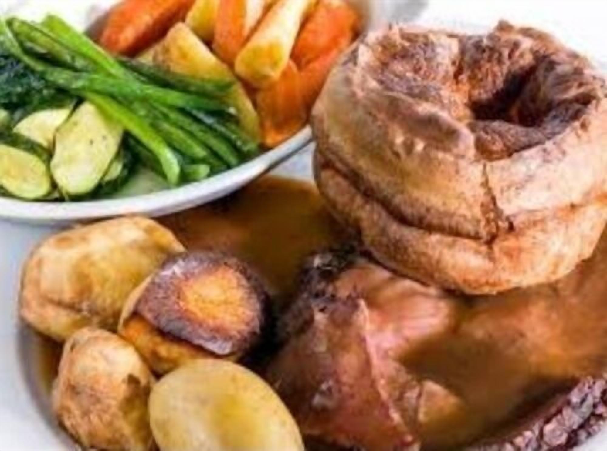 A traditional roast dinner with Yorkshire pudding, vegetables, and gravy.