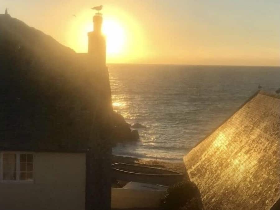 A sunset over the sea with buildings in the foreground.