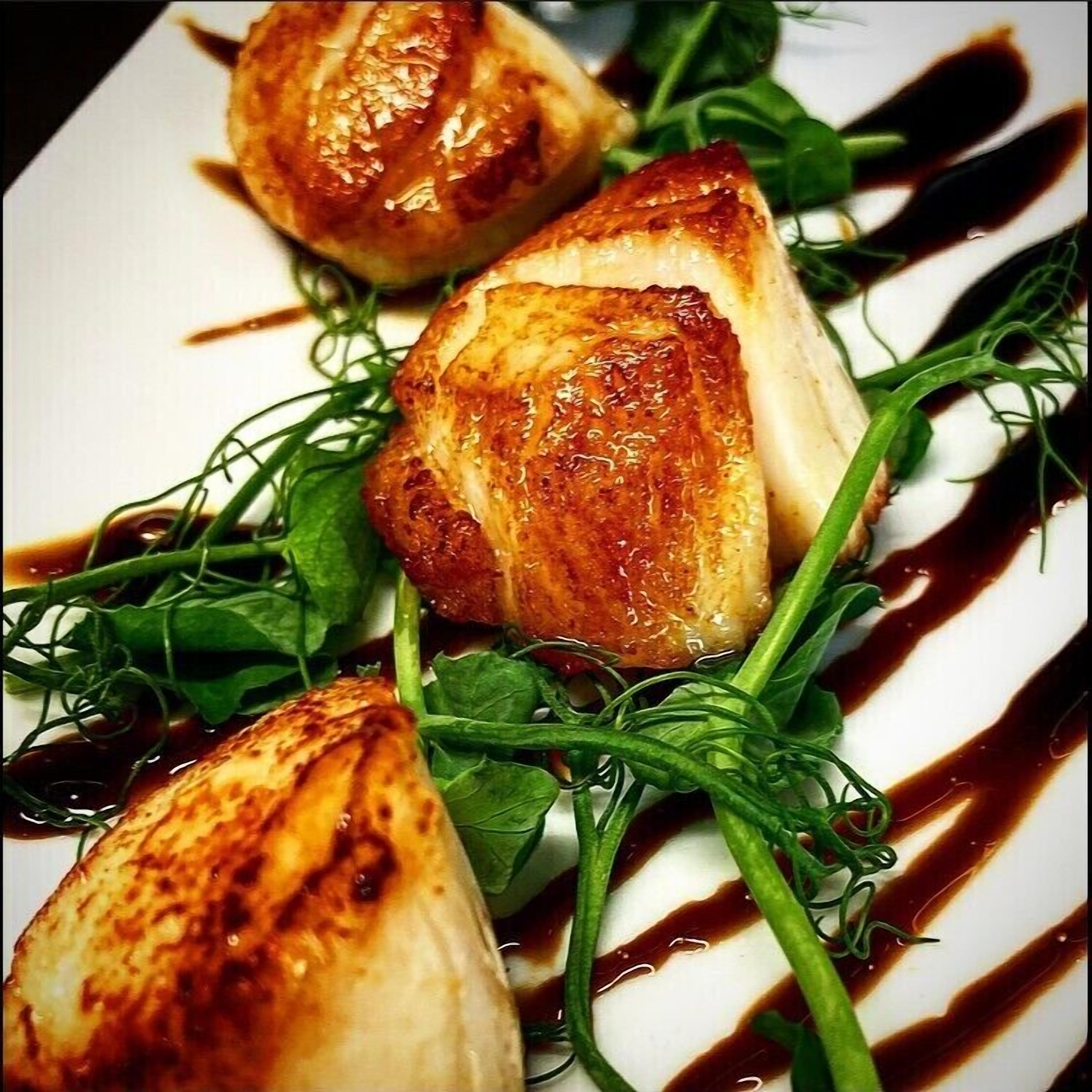 A plate with grilled chicken, greens, and a drizzle of sauce.