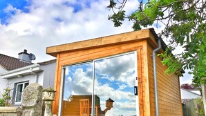 Una estructura de madera con amplios ventanales de vidrio que reflejan el cielo y las nubes.