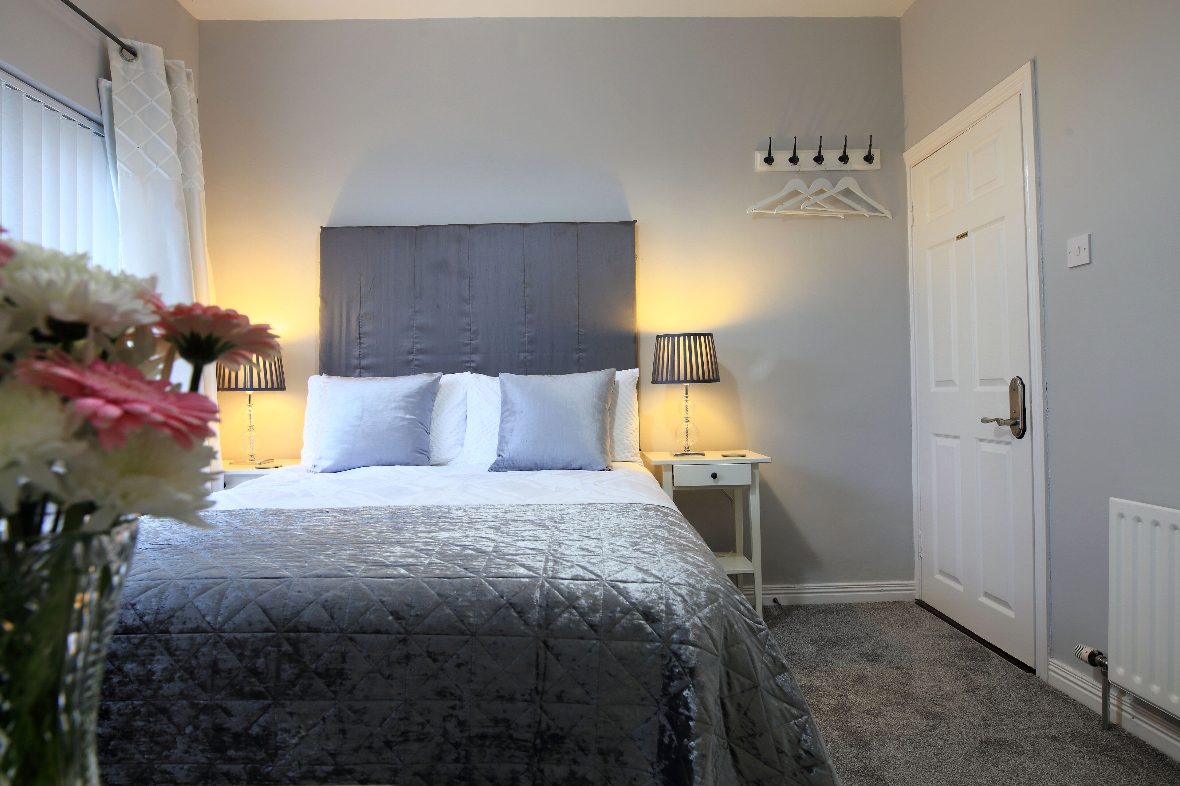 Une chambre à coucher avec un lit, des lampes de chevet, une table de chevet, une porte et un radiateur.