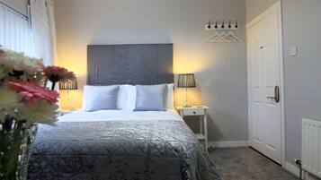 Une chambre à coucher avec un lit, des lampes de chevet, une table de chevet, une porte et un radiateur.
