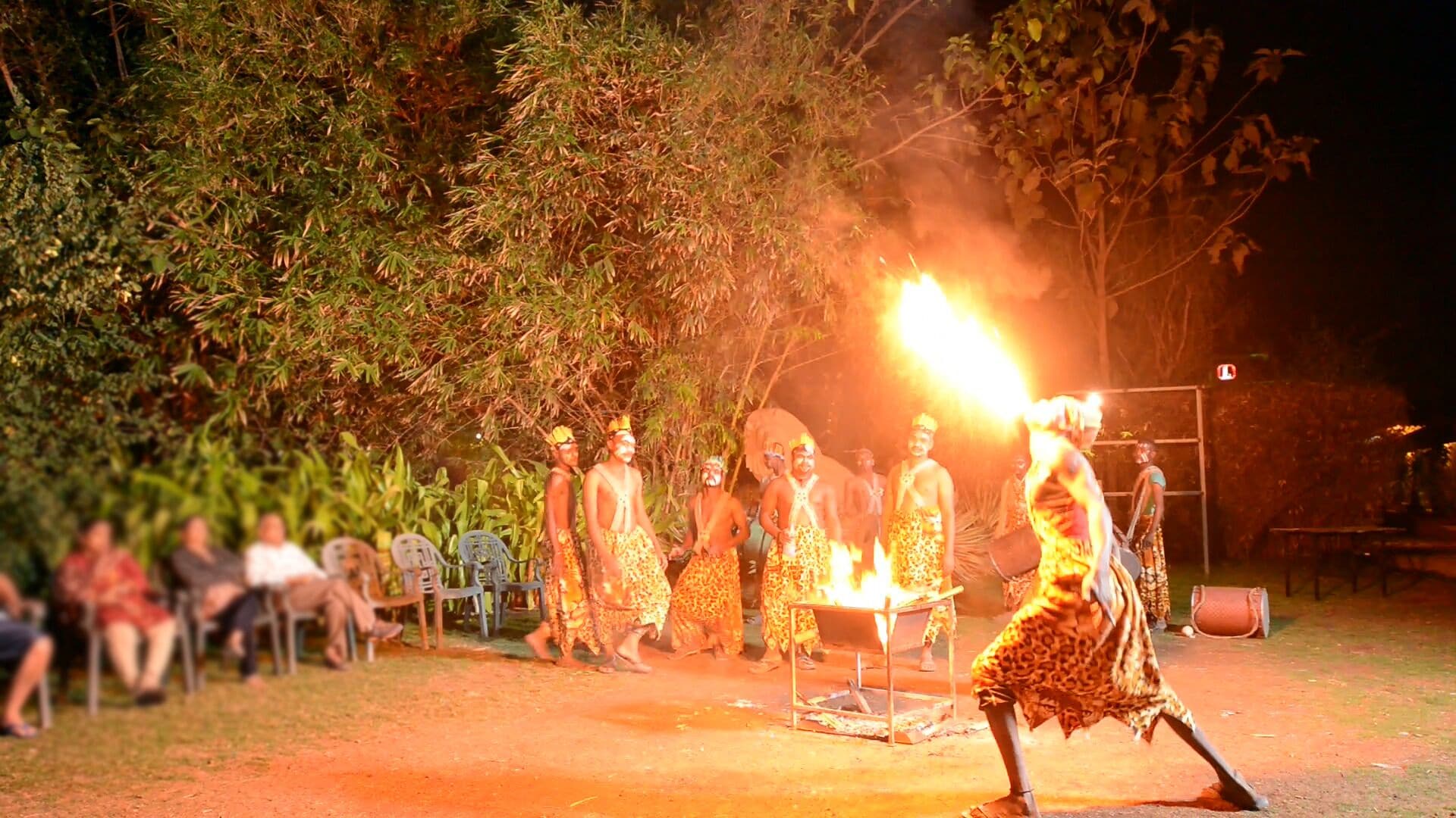 A group of people in traditional attire performing a fire ritual outdoors at night.