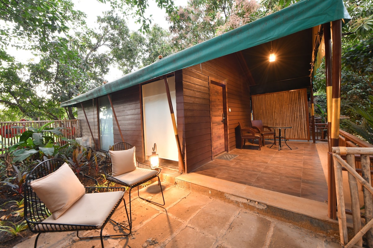 A wooden cabin with a covered patio, a dining area, and a seating arrangement.